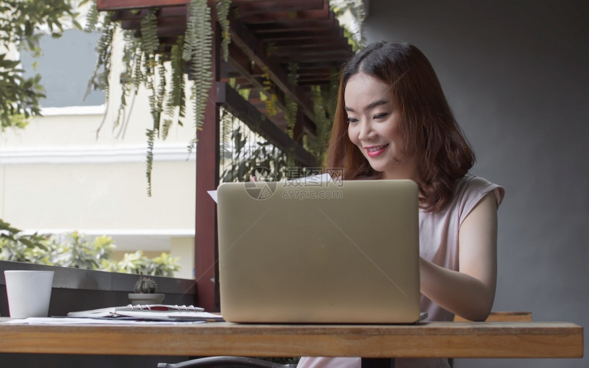 活的一名亚洲美女正在使用笔记本电脑和移动话来规划工作并在家里闲暇放松图片