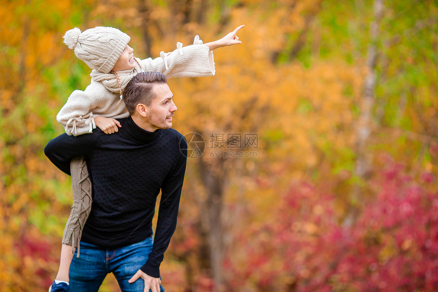 父亲背着女儿在秋天公园玩耍图片