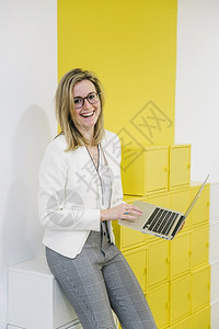 成功秘书桌子用笔记本电脑办公室的笑女人图片