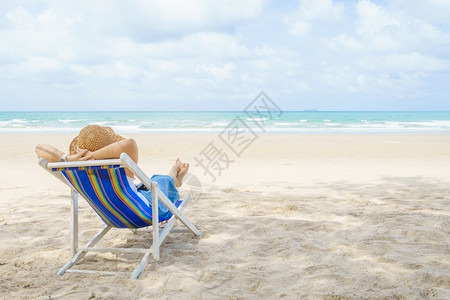 年轻的美丽亚洲年轻女子在太阳下放松海边滩的椅子上坐着沙享受观视大海的风景夏假和旅行度时蓝天与色空的堂热带图片