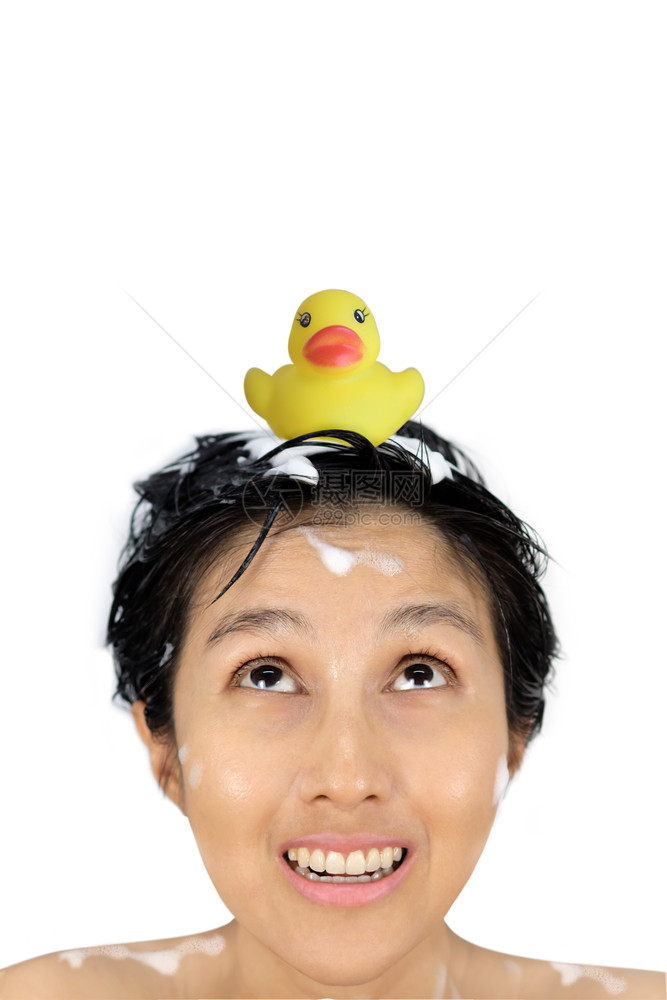 浴室黄色鸭子在一位正洗头发的亚洲女人头顶上她被白背景隔离着橡胶眼睛图片