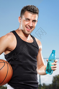 满意篮球口渴的年轻男子在体育场饮用水云图片
