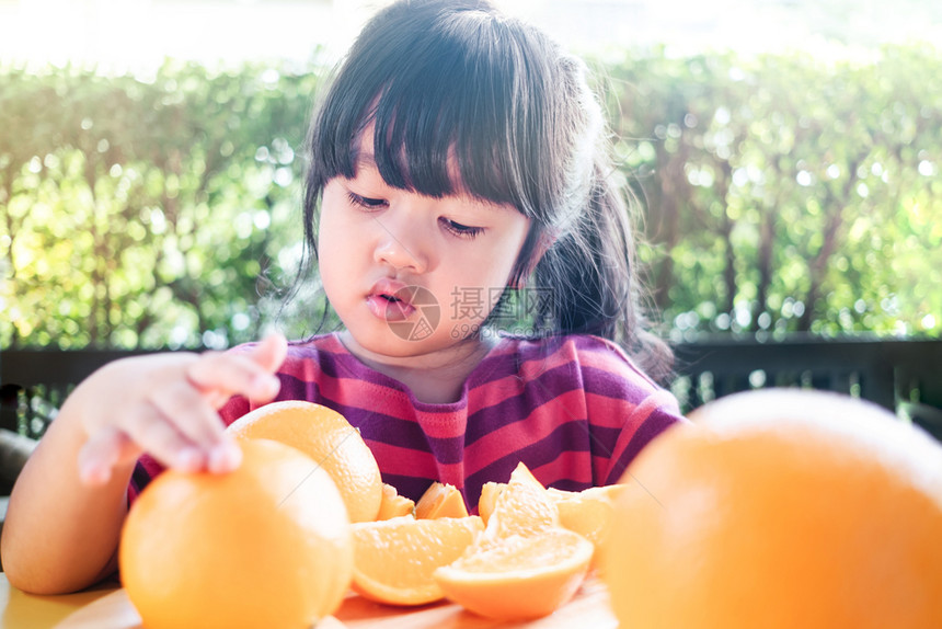 小女孩切开橘子准备食用图片