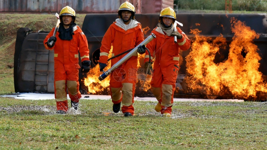 消防员用水管化学泡沫喷洒剂发动机与火焰战斗的消防员Fierman戴硬帽身穿防火灭器方面的营救训练制服热的斗争帽子图片