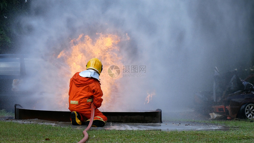 安全消防员用水管化学泡沫喷洒剂发动机与火焰战斗的消防员Fierman戴硬帽身穿防火灭器方面的营救训练制服危险的软管图片