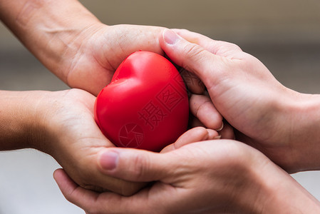将红心贴近手作为脏捐赠者给予红心作为爱的情人节日医疗呼吸器和捐心者慈善悲与健康之征兆帮助医生亲手为自由命献身女士妈棕榈背景