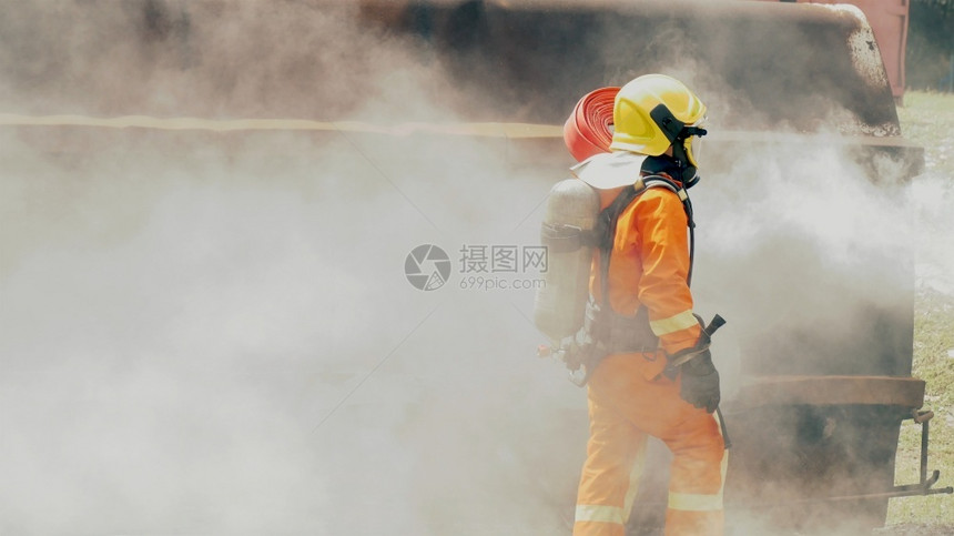 黄色的财产熄灭消防员用水管化学泡沫喷洒剂发动机与火焰战斗的消防员Fierman戴硬帽身穿防火灭器方面的营救训练制服图片