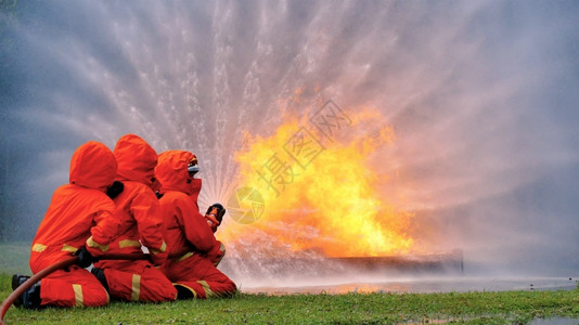 帽子紧急情况消防员用水管化学泡沫喷洒剂发动机与火焰战斗的消防员Fierman戴硬帽身穿防火灭器方面的营救训练制服危险的英雄高清图片素材