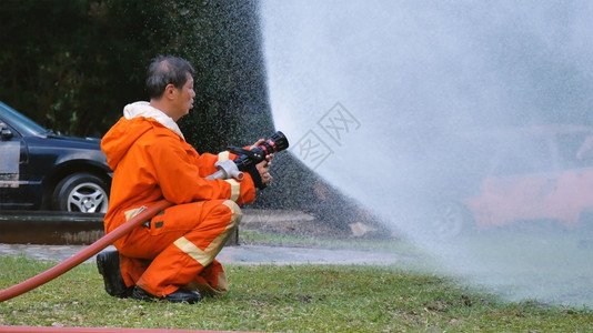 战斗机热的危险消防员用水管化学泡沫喷洒剂发动机与火焰战斗的消防员Fierman戴硬帽身穿防火灭器方面的营救训练制服保护高清图片素材