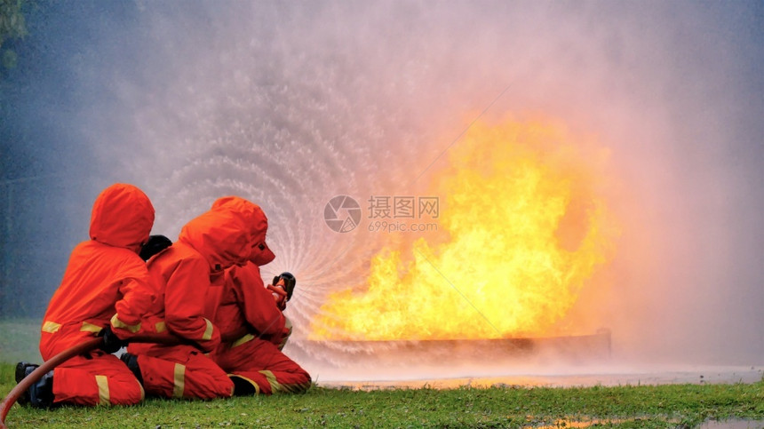 熄灭消防员用水管化学泡沫喷洒剂发动机与火焰战斗的消防员Fierman戴硬帽身穿防火灭器方面的营救训练制服套装男人图片