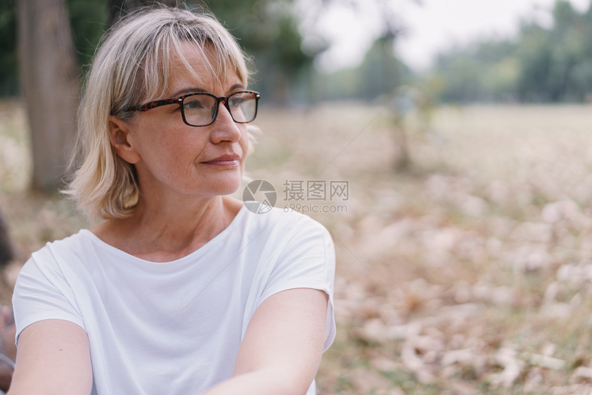 祖母松弛年长的天主教妇女秋在公共园坐着思考时戴眼镜同佩欧洲的图片
