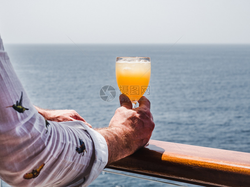 红酒杯夏天在蓝海浪背景下游轮露天甲板上盛着一杯美丽的葡萄酒时装男子观光特切休闲和旅行概念观光特近视闲暇和旅游概念假期图片