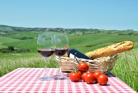 生活藤蔓柏红葡萄酒面包和西红柿在彩布上与意大利的托斯卡纳风景对比图片