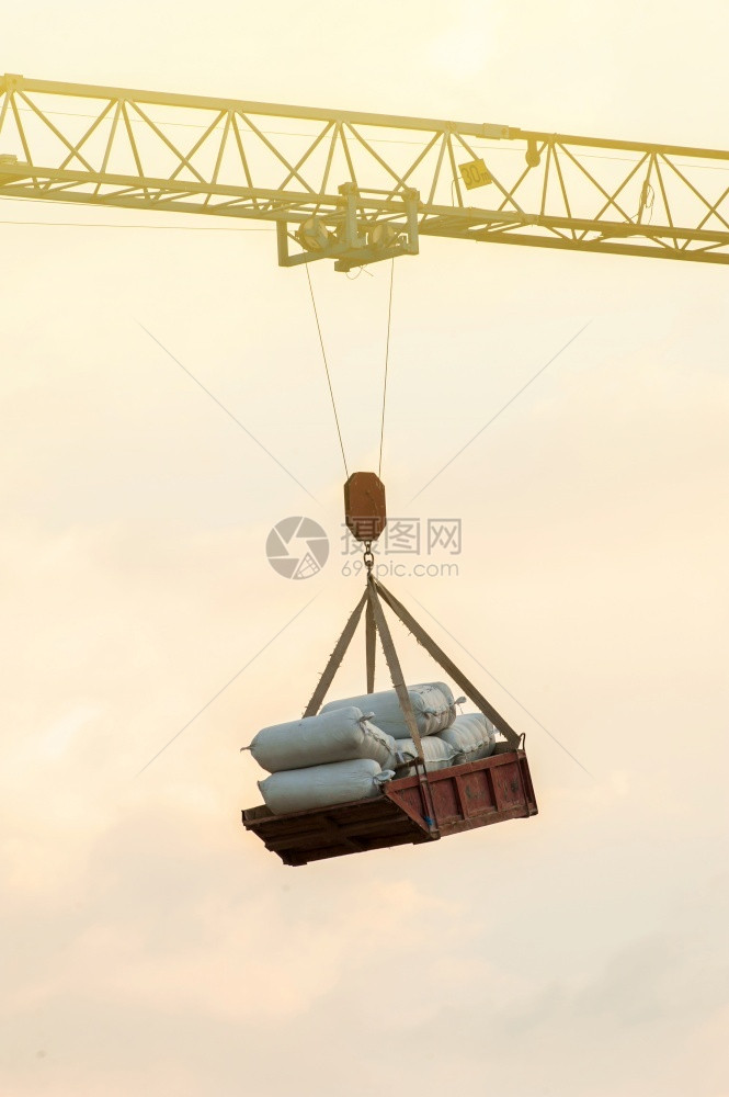 控制在建筑工地背景中的天空一个旧锤头起重机吊水泥袋托盘材料亚洲图片