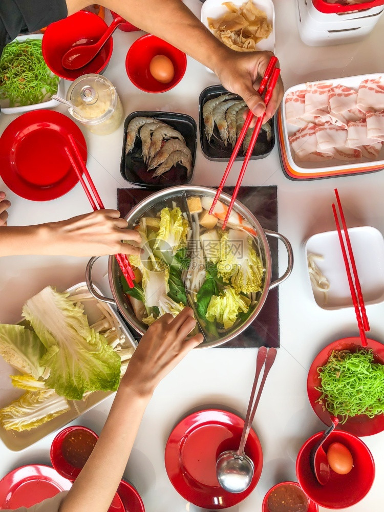 涮锅食物新鲜切片猪肉的顶端景色在热锅上加筷子以及沙布和日本菜蔬在热锅上加蔬菜的观看肉家图片