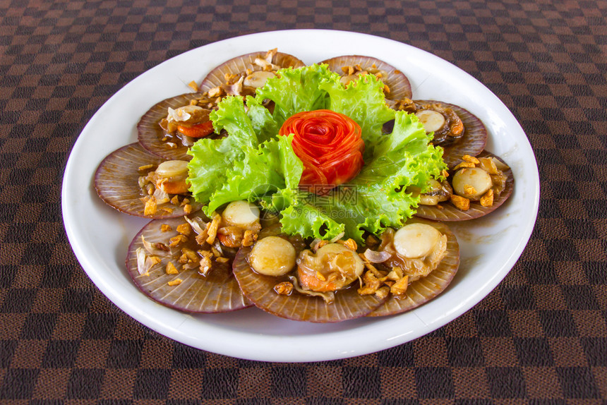 小吃营养地面用大蒜涂上胡萝卜的炸炒扇贝白陶瓷天盘上的胡萝卜放在皮革地板上图片