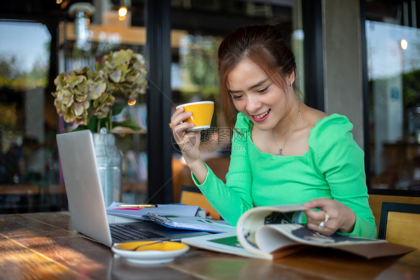 一种松弛亚洲女读书微笑快乐在成功的办公室工作后在咖啡店放松漂亮的图片