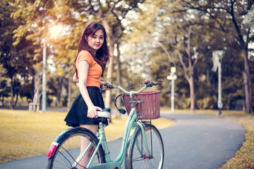 请享用亚洲人秋天公共园中的亚洲妇女肖像配有自行车人民和生活方式概念的放松娱乐和活动主题图片
