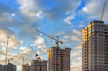 一种晴天俄罗斯莫科地区2017年6月建造新微小区筑起重机和新的住宅高楼建筑顶部以蓝色天空为敌建筑物背景图片