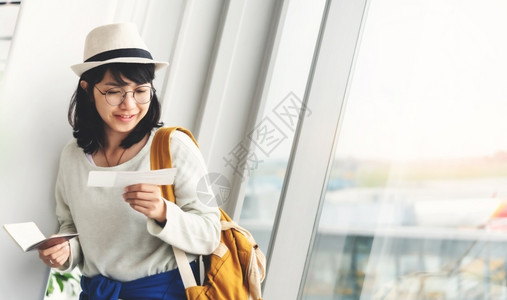 假期美丽的吸引人快乐亚洲青年妇女戴着眼镜和帽子持有护照和机场窗户附近的票戴着眼镜和帽子新鲜高清图片素材