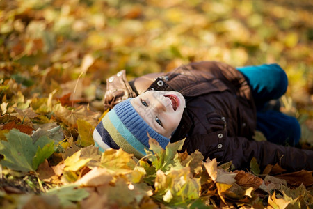 躺在秋叶上玩耍的小男孩图片
