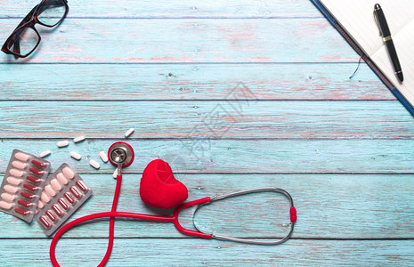 红色的红色听诊器与爱心药片背景图片