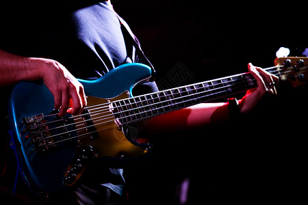 夜晚岩石音乐家拿着低吉他在夜酒厅演奏音乐会工作室图片
