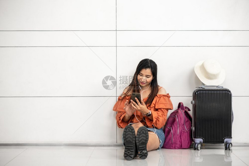 手提箱聊天在机场休息室外面旅行和人们生活方式概念中等待飞行和使用智能电话的亚洲女旅行者在机场外和游客主题交通和乘客主题吸引人的图片