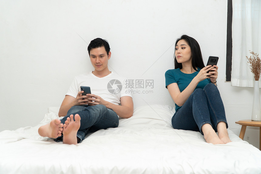已婚女孩怀疑亚洲情侣在床上时常使用智能手机但不要互相关心对方的系问题和不忠概念关系问题和不忠的概念图片