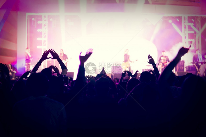 后部岩石音乐会群众在节日观看后举手向明亮的舞台灯升起快乐的图片