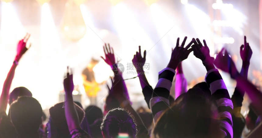 愉快音乐家夜店会群众在节日观看后举手向明亮的舞台灯升起图片