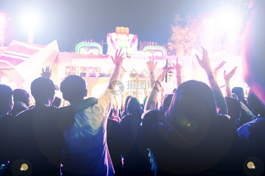 俱乐部音会群众在节日观看后举手向明亮的舞台灯升起后部人们图片