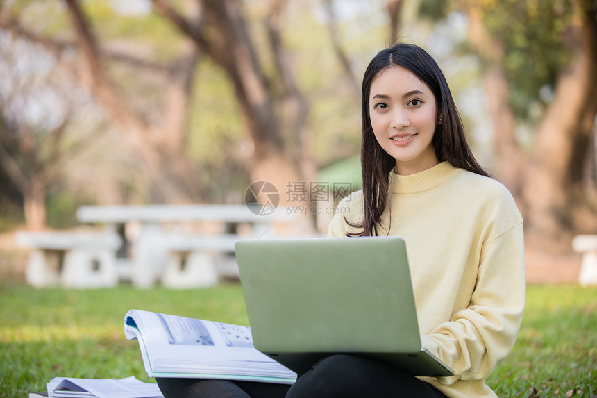 在户外草坪上使用笔记本电脑学习的女学生图片