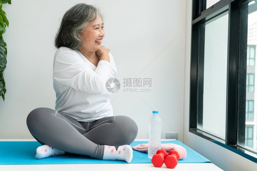 平衡人们福利上笔记本电脑在线课程的亚洲老年妇女在家中起居室练习时观看膝上型计算机在线课程网上锻炼培训概念图片
