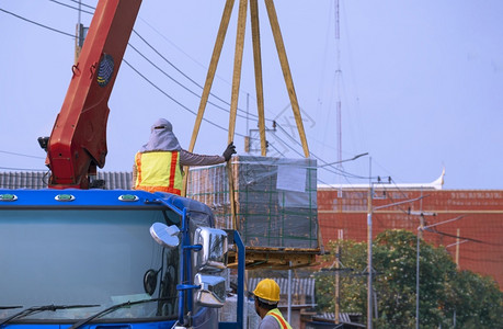 货物反光的重两名工人正在向公路建筑工地转移许多混凝土砖地板这些水泥砖铺在蓬隆卡车上背景图片