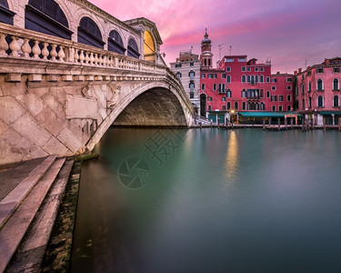 意大利威尼斯日出的里亚托桥和圣巴洛梅奥教堂暮城市景观红色的图片