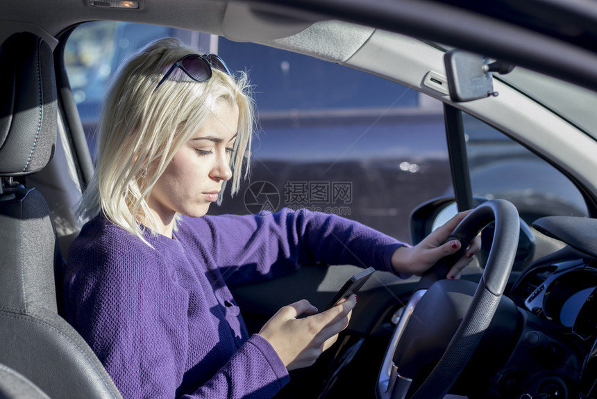 美丽的女人正在用智能手机坐车里的座位上汽车坐着经理