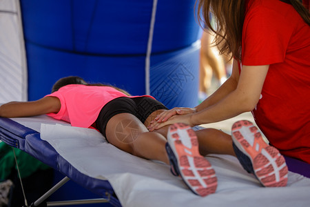 按摩运动员腿部的理疗师图片