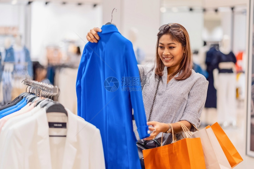 购物者中央快乐的亚洲妇女在玻璃店商选择服装在部门中心购物和狂生活方式休闲销售和黑色星期五概念中采取快乐行动欢的亚洲妇女顾客图片