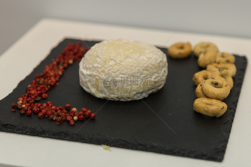 传统的白色黑桌布上涂有小红胸衣的托米诺奶酪和黑餐布上涂有小红胸和Taralli的塔拉利托米诺奶酪咸图片