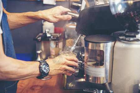 机器制服茶在意大利咖啡店厅里加牛奶的咖啡杯Cappuccucino紧握着咖啡馆的手机为客户自助餐厅制作棕色拿铁艺术棕色的高清图片素材