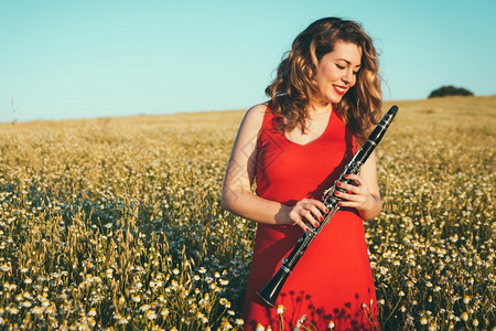 旋律穿着红裙子的女人在田里玩单簧管女孩金发图片
