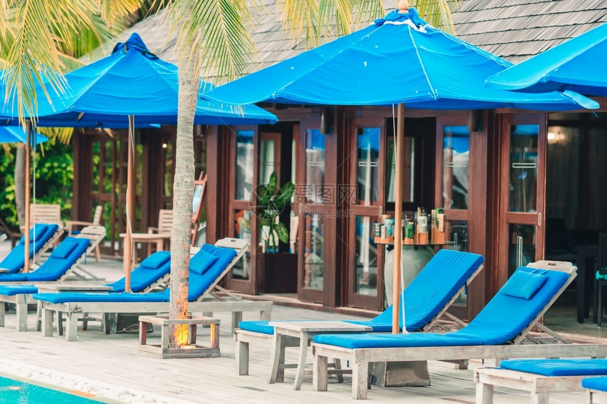 甲板夏令假期泳池边美丽热带度假村的日光浴床和雨伞美丽热带度假村的日光浴床和雨伞图片