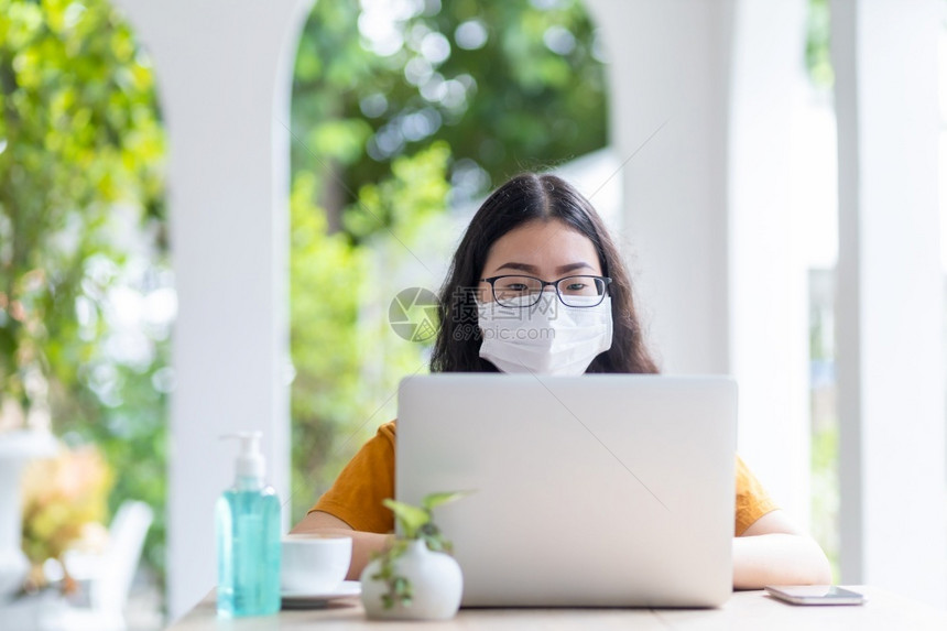 人们互联网在咖啡店用笔记本电脑工作如背景在家工作防止COVID19传播的观念等商业上穿戴保护面罩的女商人自由职业者专的图片