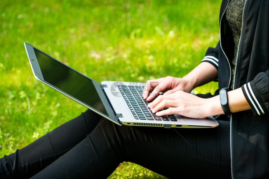 吸引人的模型在线一名妇女使用笔记本电脑坐在草地上图片