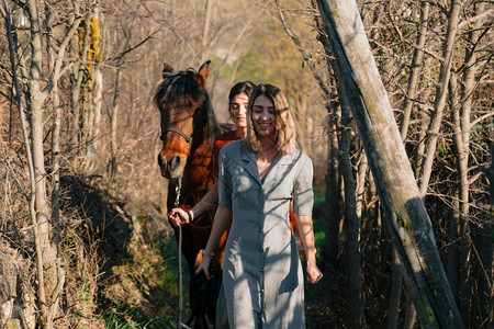 白天荒野两个女朋友聊天骑着马乘兜风穿过农村的乡间牧场图片