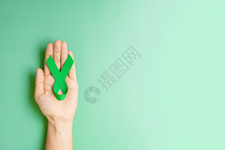 手握绿丝带预防癌症概念图片
