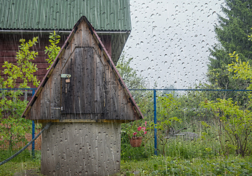 俄罗斯现代简单小屋和后院井的景象从窗户看村里有雨滴Wooden水井建筑学柳草图片