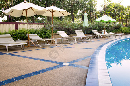 游泳池的海滩椅和雨伞反射采取休闲的游客高清图片素材