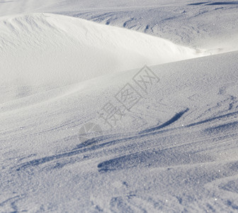 地面光滑的苍白雪表面照亮部分地表在阴影中冬季的雪漂流深移图片